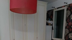 A bedroom with a bed, a wardrobe, a mirror, and a red hanging light fixture. - Casa Brezza (Scicli)