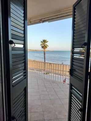 A balcony with a view of the sea, a palm tree, and a sandy beach. - Casa Brezza (Scicli)