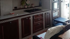 A compact kitchen with a stove, oven, and a small dining area. - Casa Brezza (Scicli)