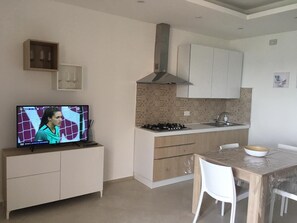 A compact kitchen with a TV, a dining area, and a small cabinet. - Casa Stella marina (Pozzallo)