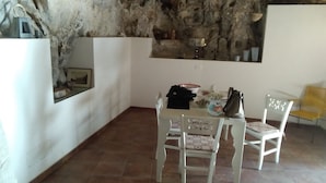 A dining area with a rustic stone wall, a white table, and two white chairs. - Grotta Paradiso (Modica)