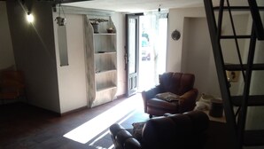 A living room with a brown leather armchair, a wooden bookshelf, and a door leading outside. - Grotta Paradiso (Modica)