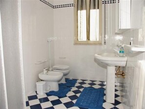 A bathroom with a checkered floor, a sink, a toilet, and a bidet. - Villa Choco (Modica)