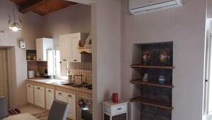 A compact kitchen with white cabinets, a built-in oven, a small white cabinet with drawers, and a stone shelf unit. - La casa di Viola (Modica)