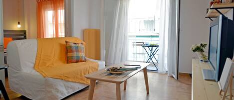 A room with a white sofa, a wooden table, and a view of a balcony with a railing.