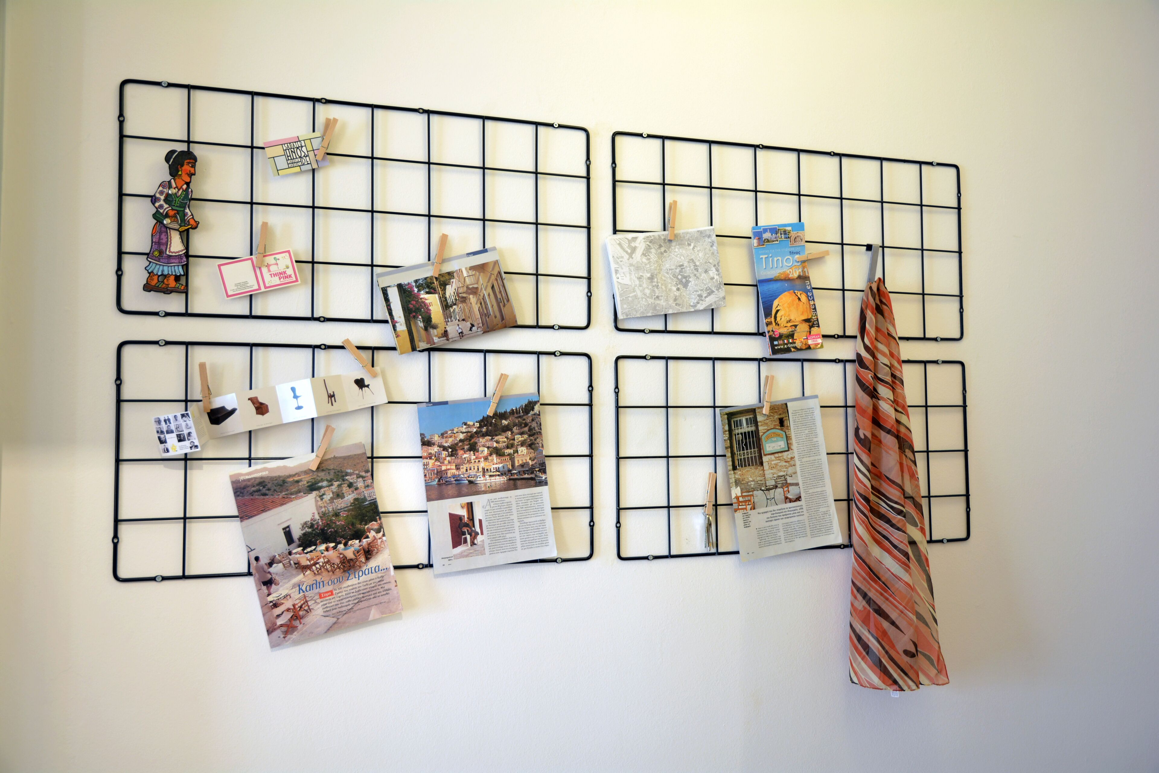 A wall with four black metal grids, each holding various papers and photographs.