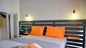 Una cama bien hecha con una toalla naranja, un cabecero de madera y una mesita de noche con una lámpara.
