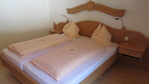 Una cama doble con cabecera de madera, dos mesitas de noche y una mesilla.