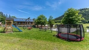 Un parque infantil con columpios, tobogán y trampolín.