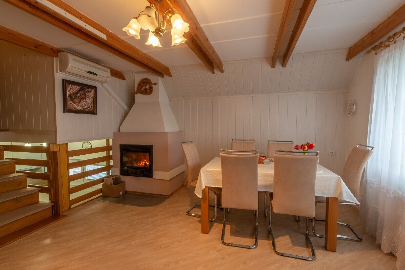 A cozy dining area with a fireplace, wooden staircase, and a table set for four.