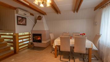 A cozy dining area with a fireplace, wooden staircase, and a table set for four.