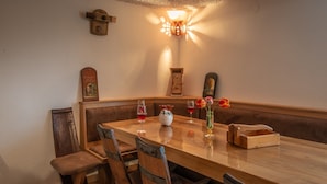 A wooden dining table with four chairs, a vase with flowers, and two wine glasses.