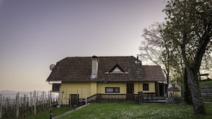 A single-story house with a sloped roof, a chimney, and a small attached structure with a bell tower.