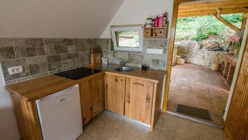 Cocina compacta con lavavajillas integrado, armarios de madera, ventana y chimenea de piedra.