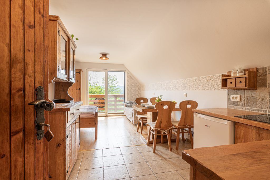 Una cocina con armarios de madera, una zona de comedor con sillas y vistas a través de un ventanal.