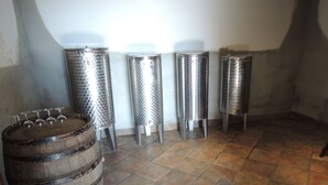 Una habitación con un barril de madera, cuatro taburetes de metal y suelo de baldosas.