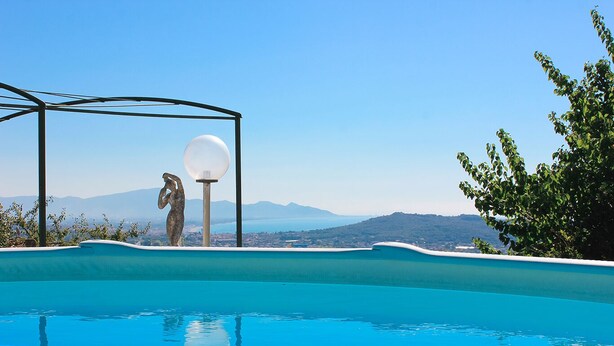 A swimming pool with clear blue water, a pergola with a sculpture, and a view of distant mountains. - The Villa of Lemons - Panoramic Villa with pool (Formia)
