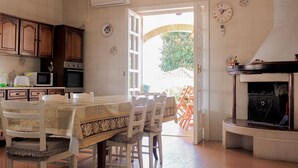 A kitchen with wooden cabinets, a dining table, chairs, a microwave, an oven, and a fireplace. - The Villa of Lemons - Panoramic Villa with pool (Formia)