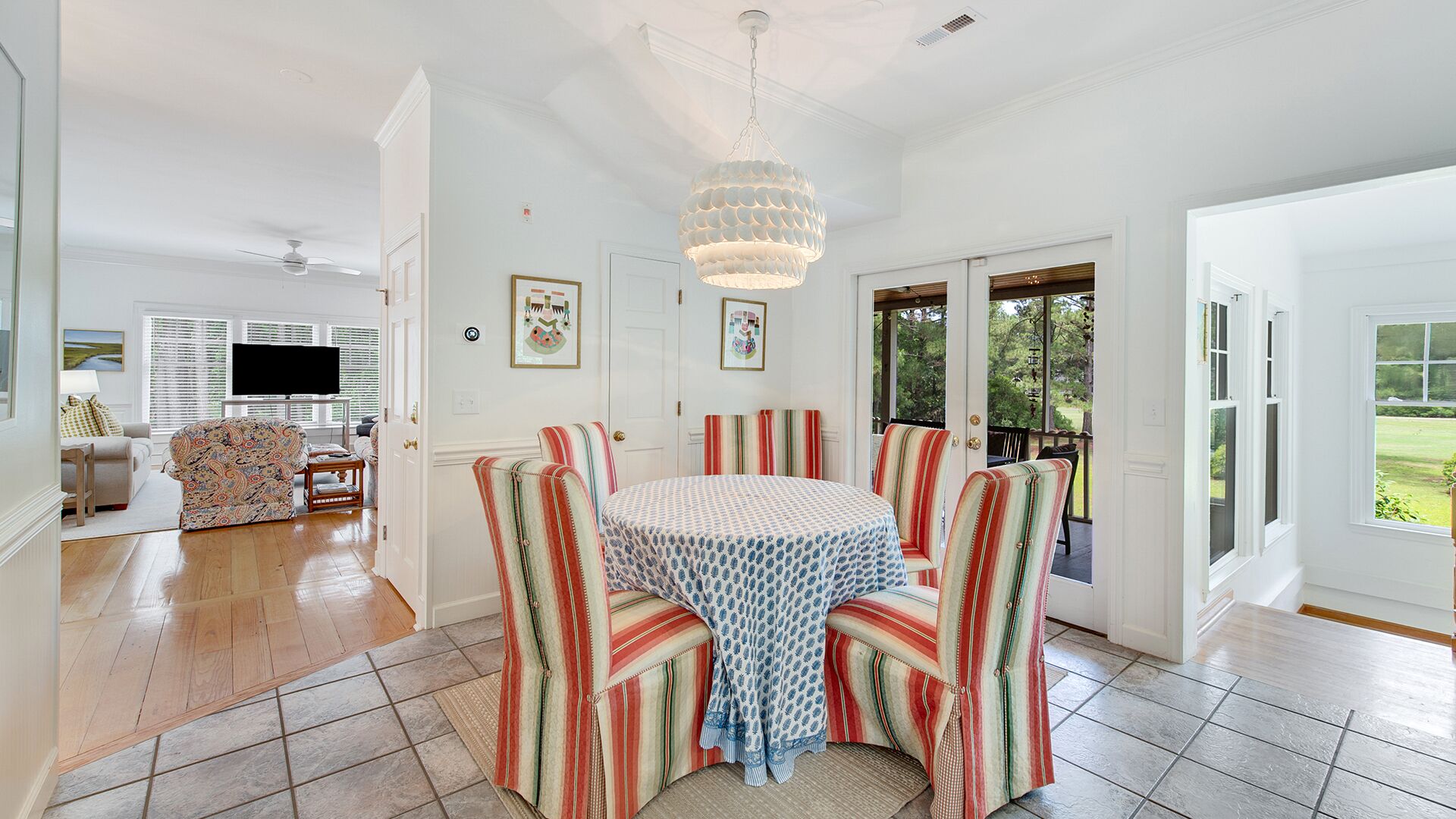 A dining area with striped chairs, a round table, and a chandelier.