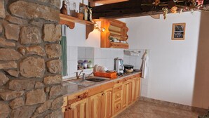 Eine Küche mit Steinwänden, Holzschränken und einer gefliesten Spritzschutzwand.
