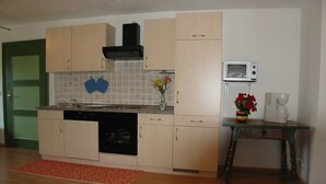 Una cocina compacta equipada con lavavajillas, horno, microondas y una pequeña mesa con cafetera.