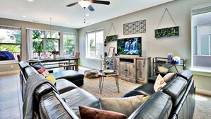 A spacious living room with a leather couch, a coffee table, and a TV.
