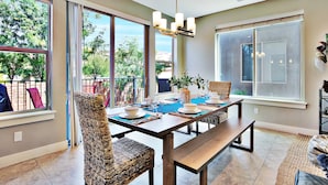 A dining area with a large table, chairs, and a hanging light fixture.