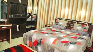 Een slaapkamer met een bed, een televisie, een kledingkast en een gestreepte wand.