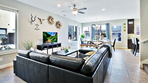 Una sala de estar moderna con un sofá de cuero, un televisor de pantalla plana y decoración en la pared.