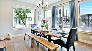 Un comedor con una mesa de madera, bancos y sillas. Hay una araña colgante sobre la mesa.