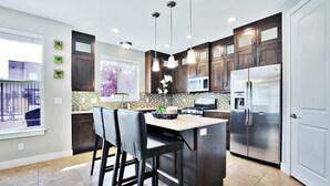 Una cocina moderna con armarios de madera oscura, electrodomésticos de acero inoxidable y una isla central con taburetes de bar.