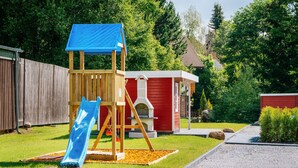 A playground with a blue slide and a wooden playhouse. - Bode-Apartments (Oberharz am Brocken)