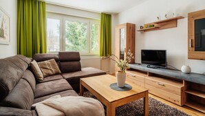 A modern living room with a sectional sofa, a wooden coffee table, a flat-screen TV, and a built-in entertainment unit. - Bode-Apartments (Oberharz am Brocken)