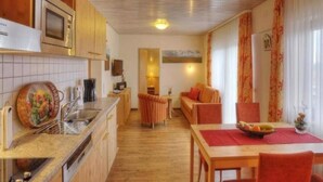 Une cuisine compacte avec des meubles en bois, un four à micro-ondes et un coin repas comprenant une table et des chaises.