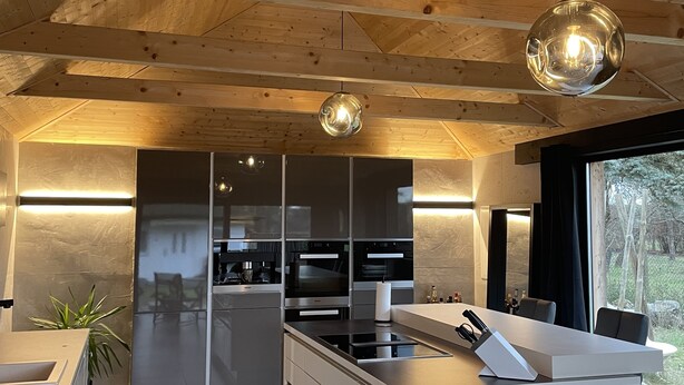 Una cocina moderna con vigas de madera en el techo, electrodomésticos de acero inoxidable y una isla central.