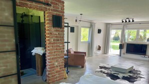 Habitación amplia con pared de ladrillo, un gran ventanal, un sofá y un tapete de cuero de vaca.