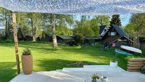 Un patio al aire libre con una mesa y sillas, rodeado de césped y árboles.