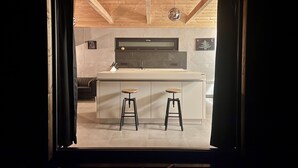 Una cocina moderna con una isla grande, dos taburetes y un horno empotrado.