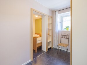 A bedroom with a bed, a wardrobe, a small table, and a window with a plant. - Group Getaway in Amel (Amel)
