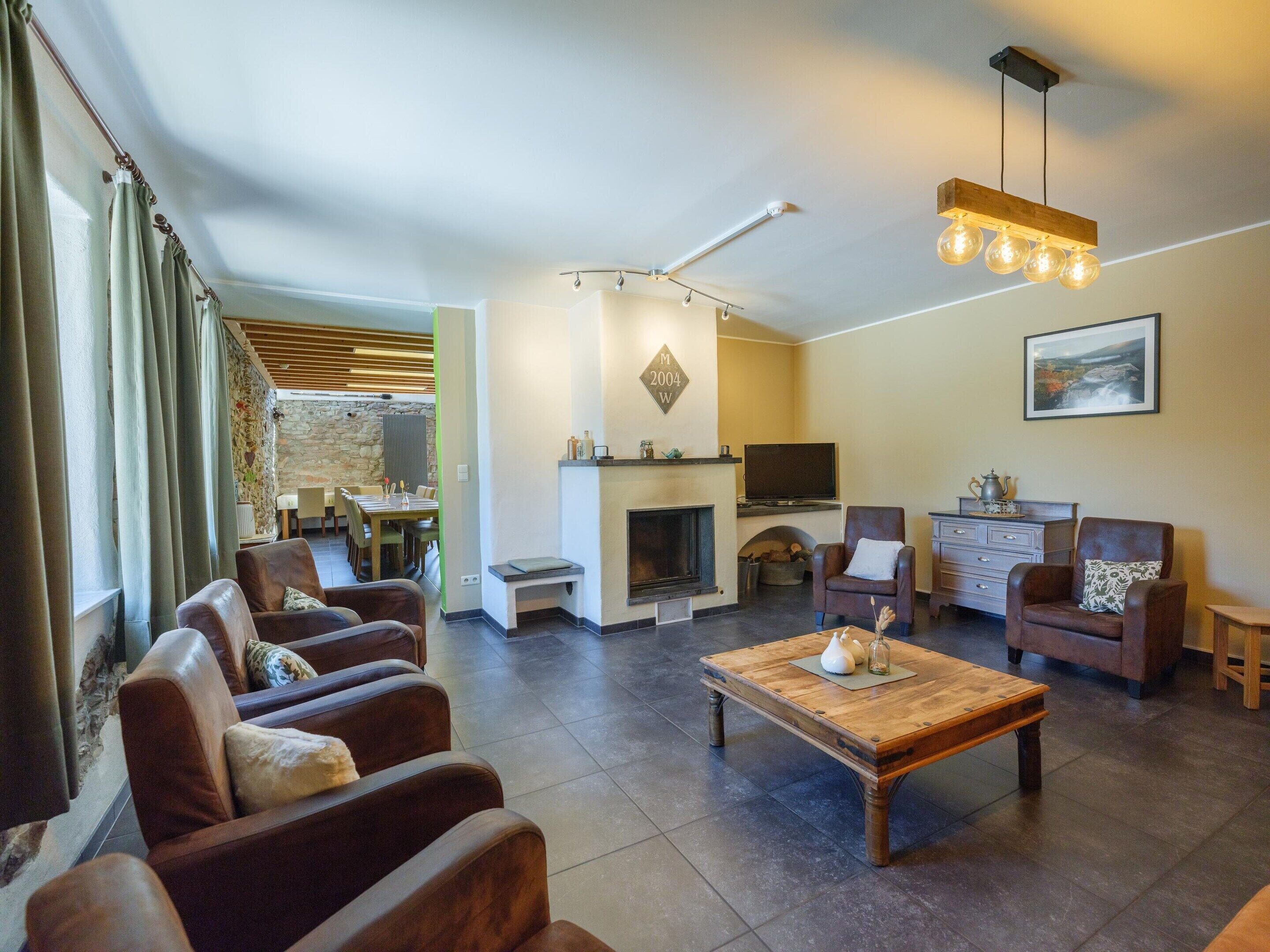 A modern living room with leather sofas, a wooden coffee table, a fireplace, and a television.
