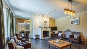A modern living room with leather sofas, a wooden coffee table, a fireplace, and a television. - Group Getaway in Amel (Amel)
