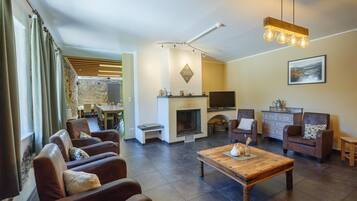 A modern living room with leather sofas, a wooden coffee table, a fireplace, and a television.