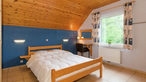 A bedroom with a wooden bed, a desk, and a window with curtains. - Spacious Retreat by Lake (Waimes)