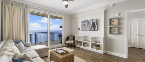 A living room with a sofa, ottoman, and a white entertainment unit.