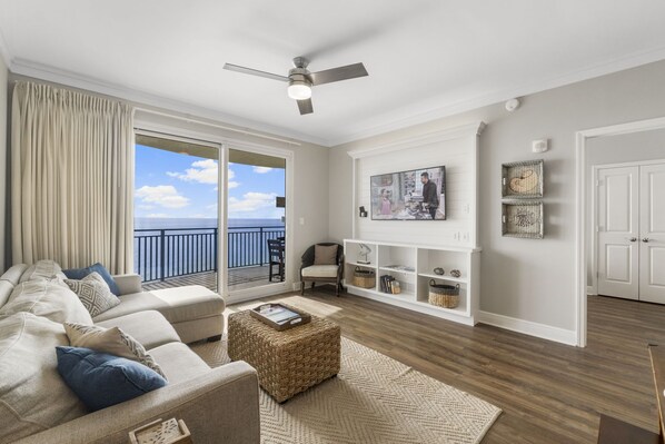 A living room with a sofa, ottoman, and a white entertainment unit. - Amazing Gulf Front Unit for 8!beach srvc included!!! (Panama City Beach)