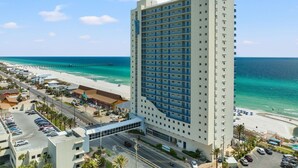 A high-rise hotel with a beach view, featuring a large parking lot and a beachfront promenade. - Amazing Gulf Front Unit for 8!beach srvc included!!! (Panama City Beach)