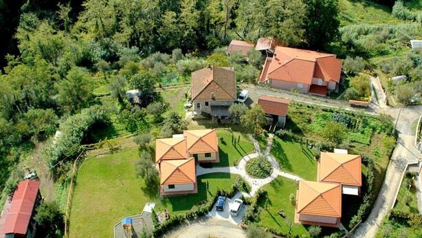 A residential area with multiple houses, each featuring a red-tiled roof and surrounded by greenery. - Belvilla by OYO Montebello Bilo A (Bolano)