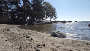 A sandy beach with large rocks and trees in the background. - Alholmens Bad o Camping (Sölvesborg)