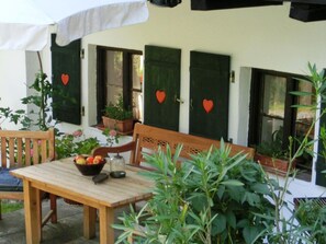 An outdoor seating area with a wooden table and chairs, surrounded by potted plants and a white umbrella. - Chalet in Kollnburg Near St. Englmar Ski Area (Kollnburg)