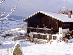 A wooden cabin with a sloped roof, a porch with benches, and a view of snow-covered hills. - Chalet in Kollnburg Near St. Englmar Ski Area (Kollnburg)